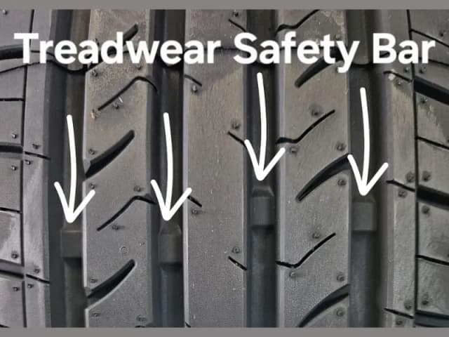 Tyre tread with arrows pointing to the treadwear safety bars